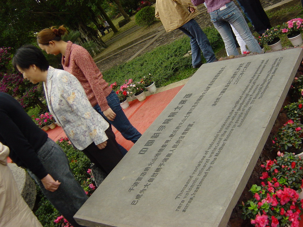 Miaomiao`s mother at a stone with inscription at the entrance to the Hainan Volcano Park