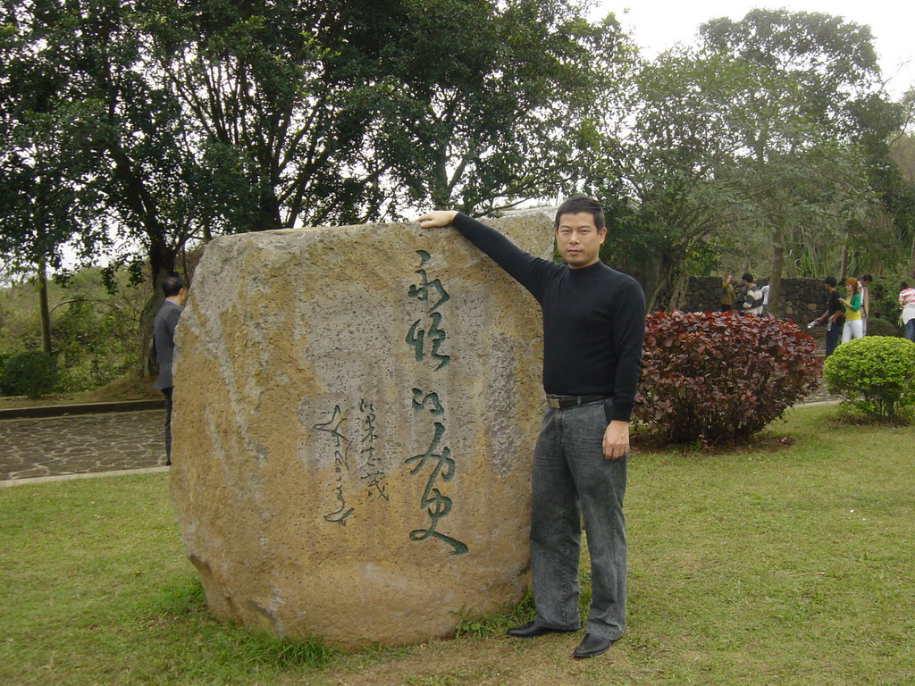 Miaomiao`s family member at a rock with inscription at the Hainan Volcano Park
