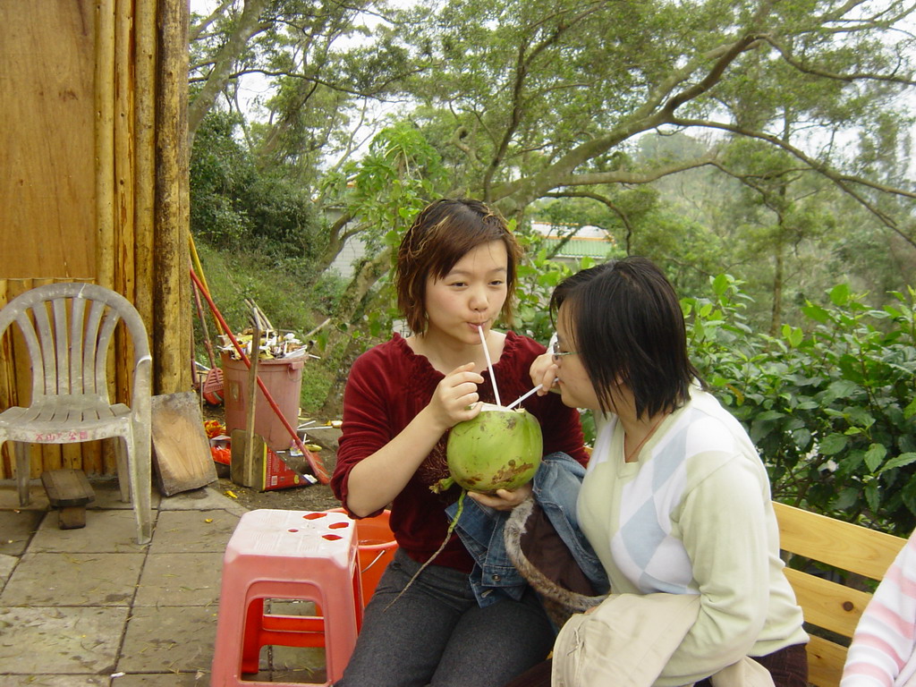 Miaomiao and her sister drinking from a coconut at the Mt. Fengluling volcano crater at the Hainan Volcano Park