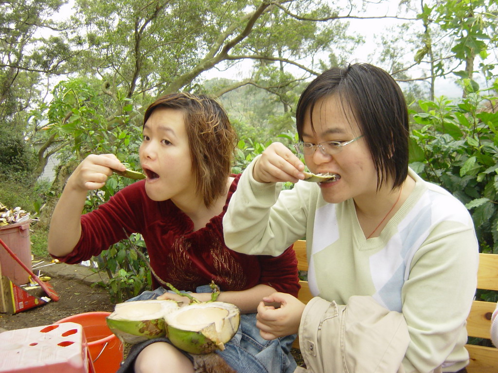 Miaomiao and her sister eating from a coconut at the Mt. Fengluling volcano crater at the Hainan Volcano Park