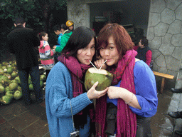 Miaomiao and Mengjin drinking from a coconut at the Mt. Fengluling volcano crater at the Hainan Volcano Park