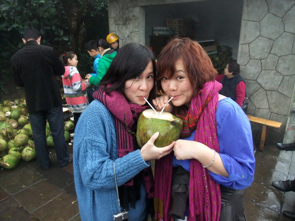 Miaomiao and Mengjin drinking from a coconut at the Mt. Fengluling volcano crater at the Hainan Volcano Park