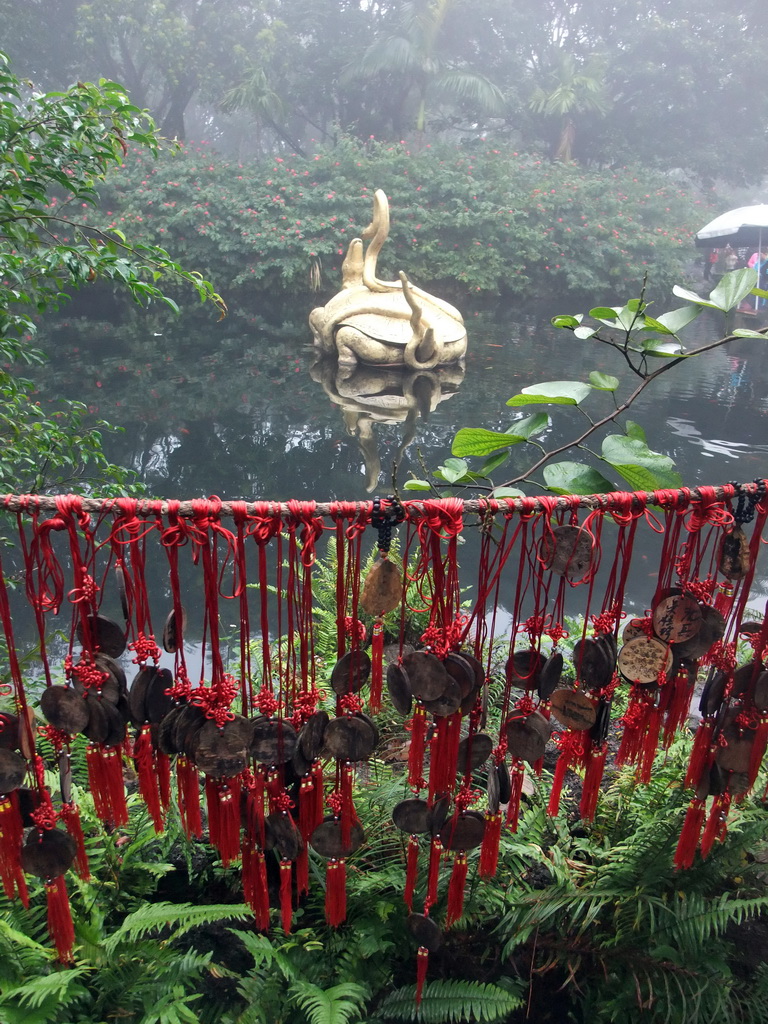 Pool with turtle and snake statue and amulets at the Hainan Volcano Park