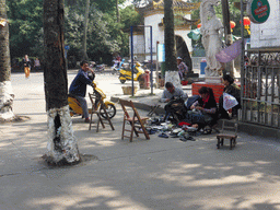 Shoemakers in front of the north entrance to Haikou People`s Park at Donghu Road