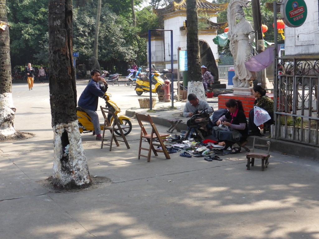 Shoemakers in front of the north entrance to Haikou People`s Park at Donghu Road