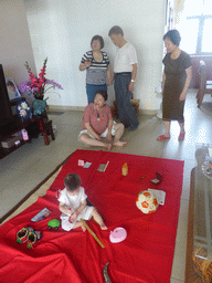 Miaomiao, Max and Miaomiao`s family during the Zhuazhou ceremony for Max`s first birthday in the apartment of Miaomiao`s parents