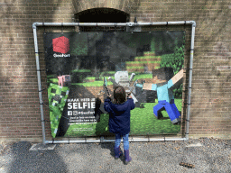 Max with a Minecraft axe in front of a Minecraft poster in front of Building A at the GeoFort