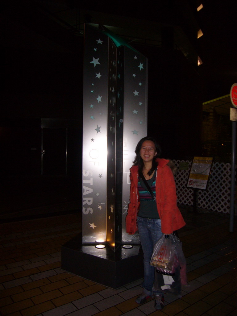 Miaomiao`s friend at a sign at the Avenue of Stars, by night