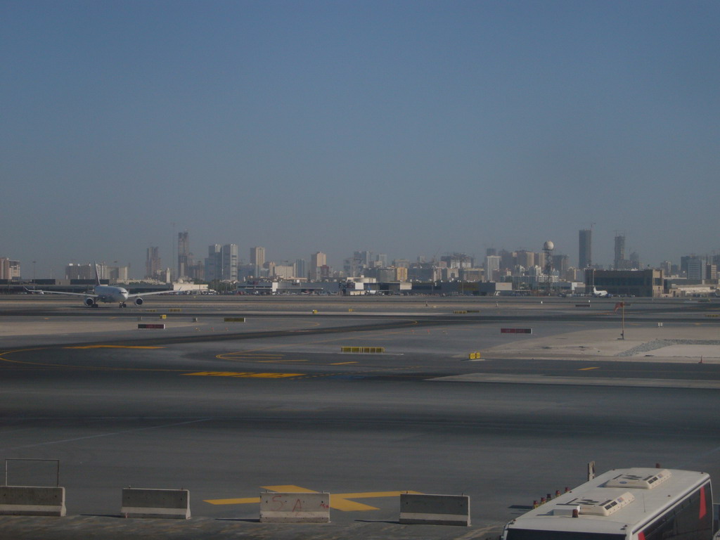 Skyscrapers in the city center of Dubai and an airplane, viewed from the Departure Gate at Dubai International Airport