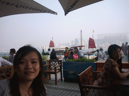 Miaomiao on the terrace of a restaurant at the Avenue of Stars, with a view on a boat in Victoria Harbour and the skyline of Hong Kong