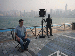 Tim on a movie director`s chair at the Avenue of Stars, with a view on Victoria Harbour and the skyline of Hong Kong