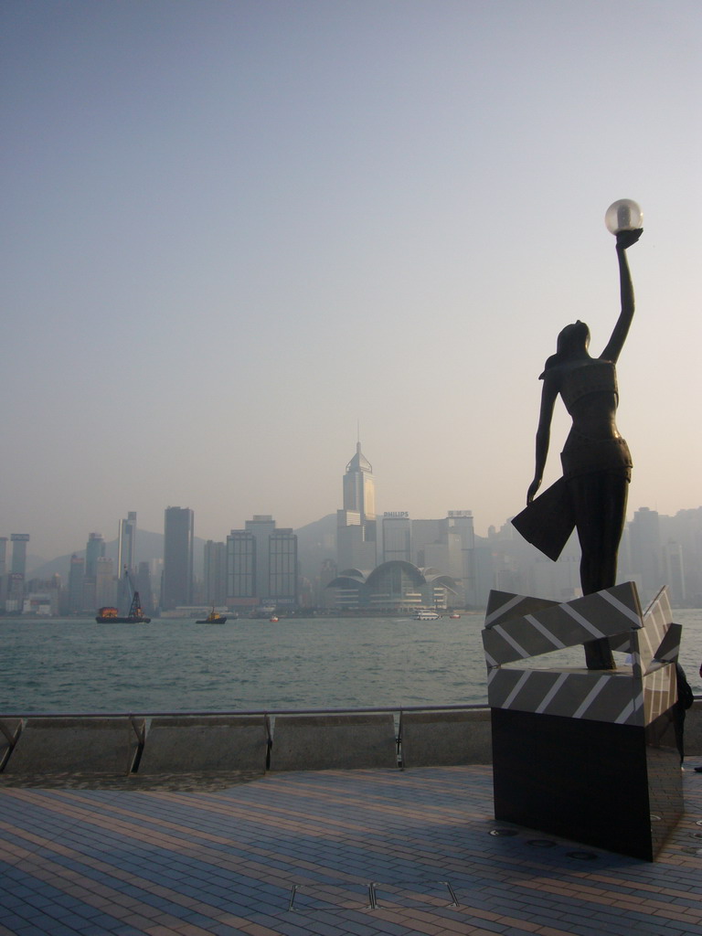 Statue at the Avenue of Stars, with a view on boats in Victoria Harbour and the skyline of Hong Kong with the Central Plaza building and the Hong Kong Convention and Exhibition Centre
