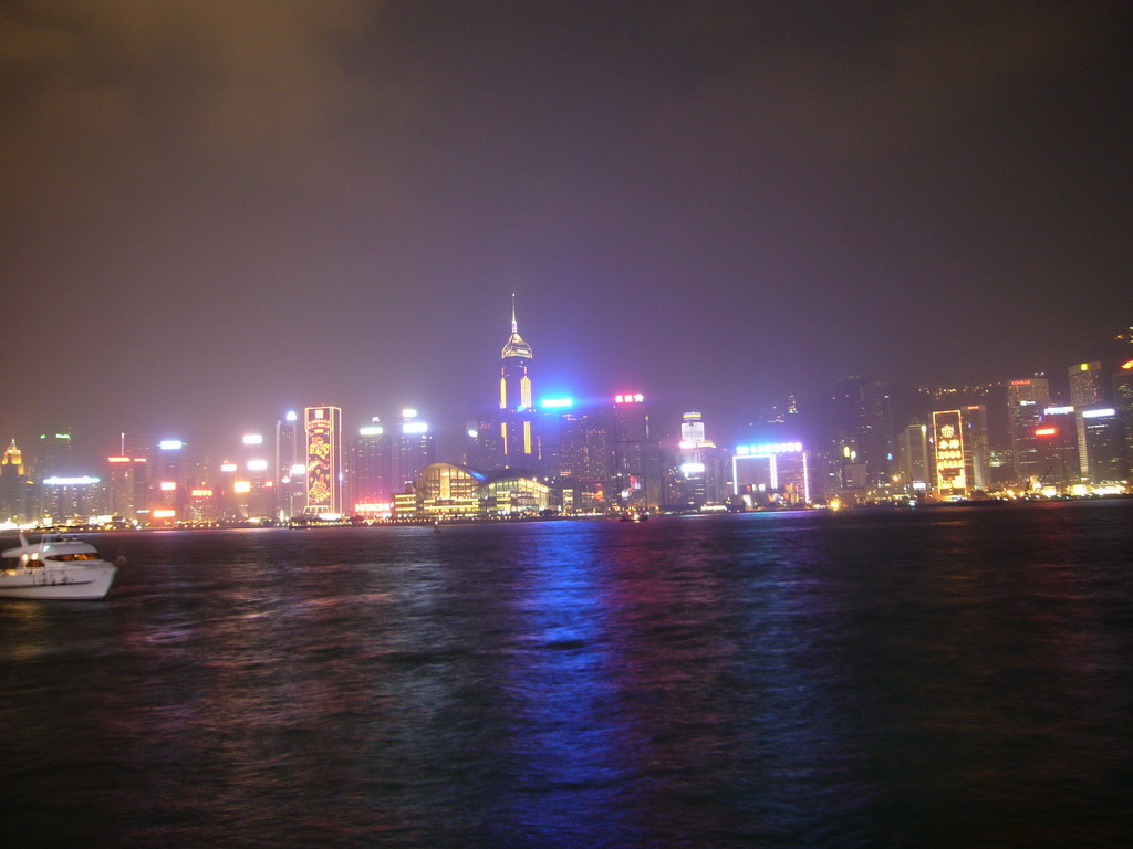 Boat in Victoria Harbour and the skyline of Hong Kong with the Hong Kong Convention and Exhibition Centre and the Central Plaza building, viewed from the Avenue of Stars, during the `A Symphony of Lights` light and sound show, by night