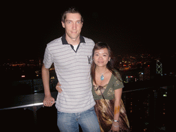 Tim and Miaomiao at Victoria Peak, with a view on the skyline of Hong Kong and Kowloon with the Bank of China Tower, and Victoria Harbour, by night