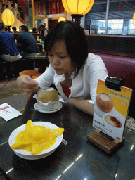 Miaomiao eating from a coconut in a restaurant at Hong Kong International Airport