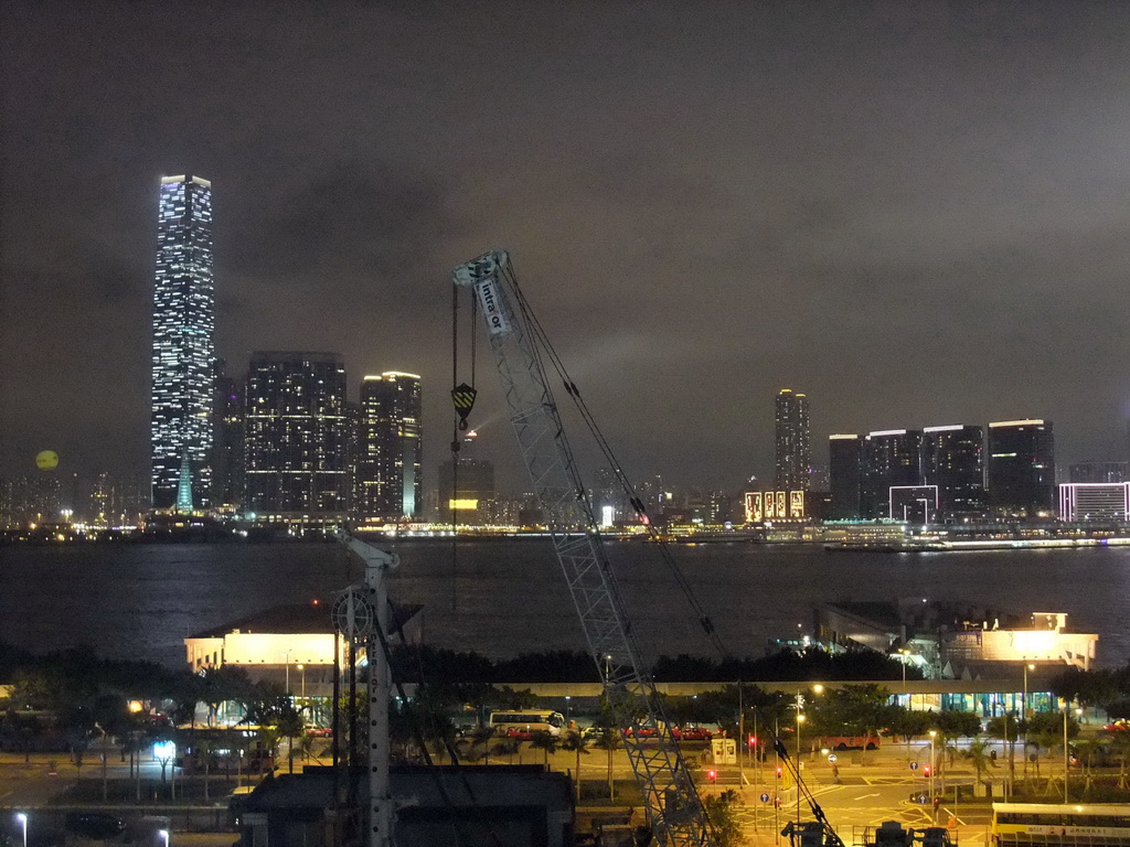 Victoria Harbour with Central Ferry Pier 5 and 6, and the skyline of Kowloon with the International Commerce Centre during the `A Symphony of Lights` multimedia show, viewed from the roof terrace of the IFC Mall, by night