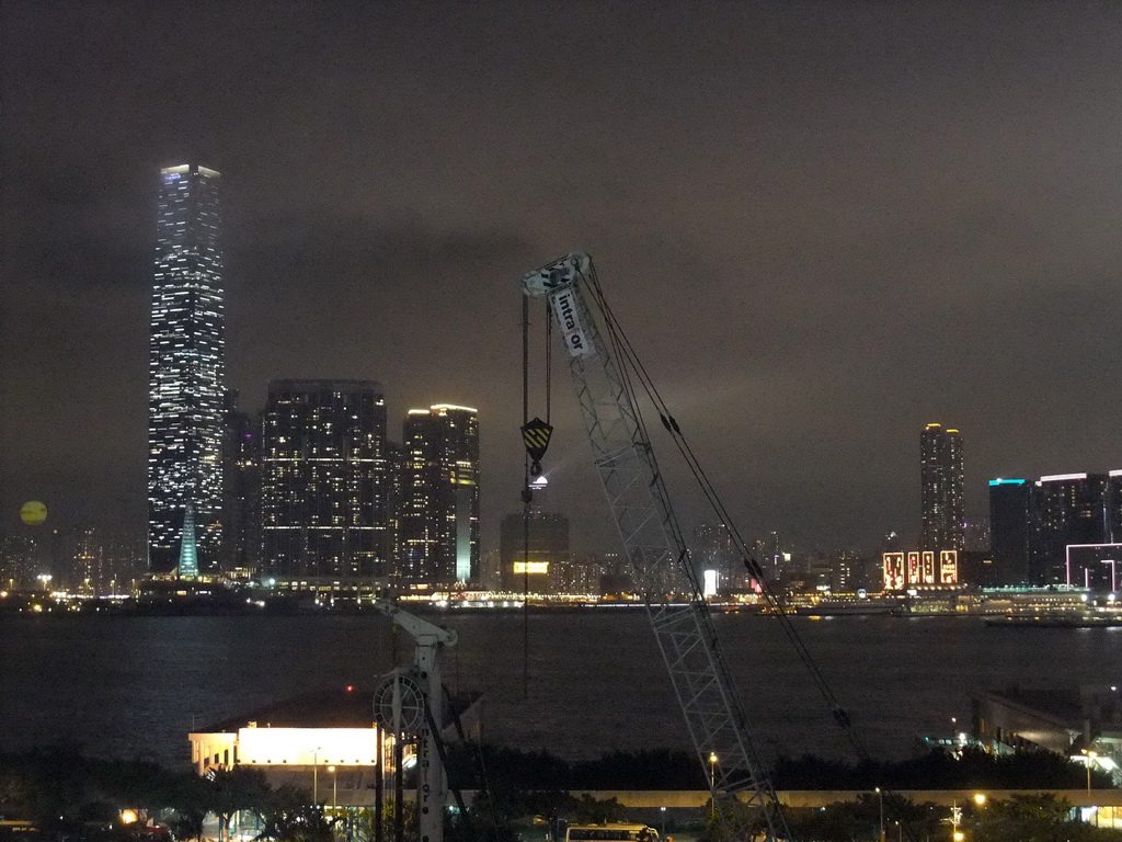 Victoria Harbour with Central Ferry Pier 5 and 6, and the skyline of Kowloon with the International Commerce Centre during the `A Symphony of Lights` multimedia show, viewed from the roof terrace of the IFC Mall, by night