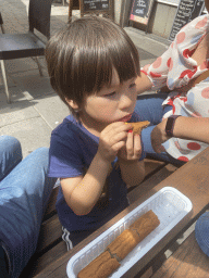 Max having a frikandel at the terrace of the Friterie Autre Chose snack bar at the Rue du Pont street