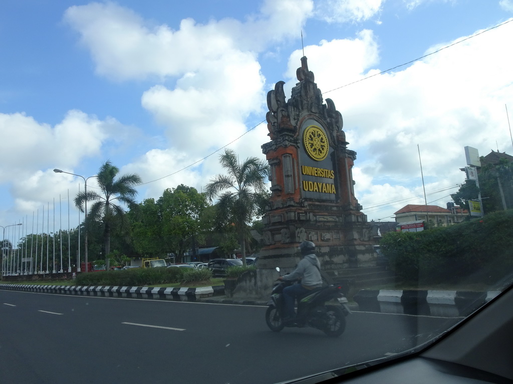 Entrance sign of Udayana University at the Jalan Raya Kampus Unud street, viewed from the taxi