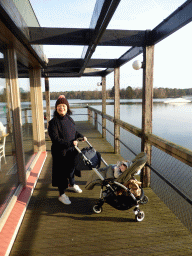 Miaomiao with Max in a trolley on a path outside the Market Dome, with a view on the west side of the main lake of the Center Parcs Kempervennen holiday park