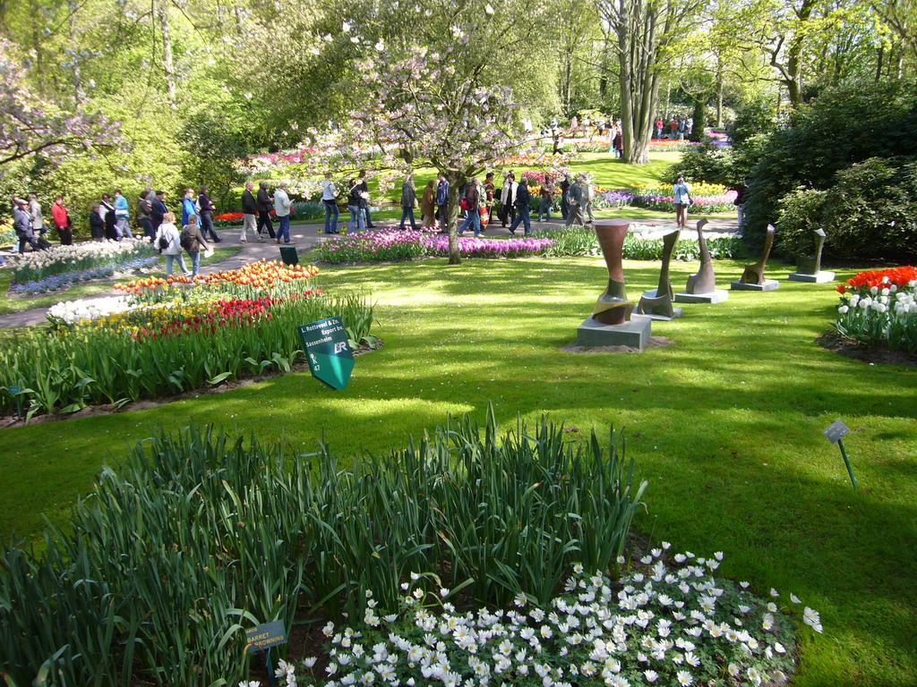 Flowers and small statues in a grassland near the central lake of the Keukenhof park