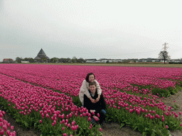 Tim and Miaomiao in a field with purple tulips and the H.H. Engelbewaarderskerk church of Lisse