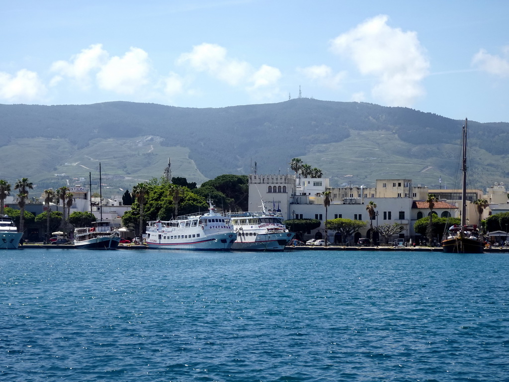 Boats and buildings at the southwest side of the Limenas Ko harbour and hills, viewed from the northwest side