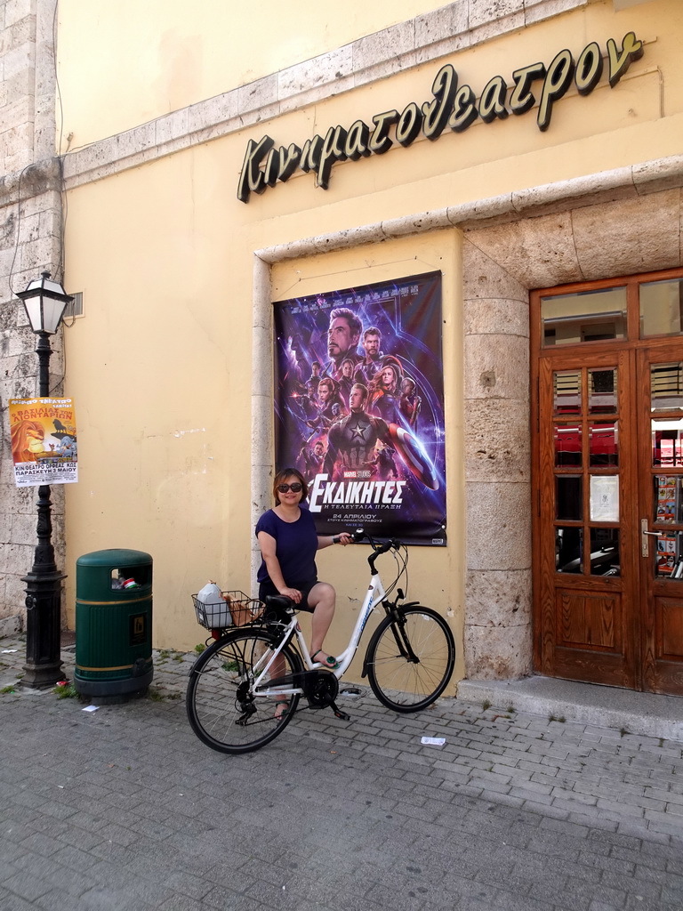 Miaomiao on the bike with a poster of the movie `Avengers: Endgame` in front of the Cine Orfeas cinema at the 25is Martiou street