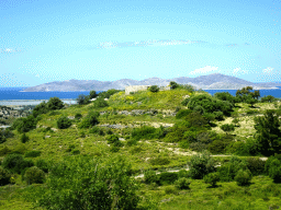 Ruins on a hill alongside the Miniera Asfendiou street, the Aegean Sea and the island of Pserimos, viewed from the tour bus