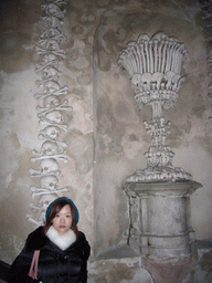 Miaomiao and a wall with skulls and bones in the Sedlec Ossuary