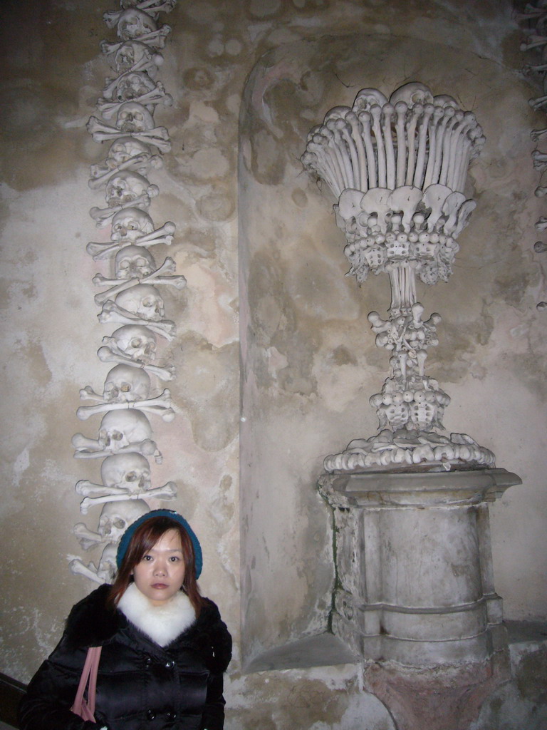 Miaomiao and a wall with skulls and bones in the Sedlec Ossuary