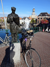 The statue `Bloemenkoopman` by Gerard Brouwer at the Visbrug bridge over the Nieuwe Rijn river, and the Hartebrugkerk church