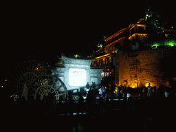 Water wheel, wall with inscriptions, stone wall and Qian Xue Lou Hotel at Yuhe Square in the Old City of Lijiang, by night