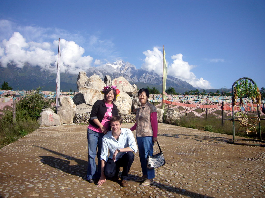 Tim, Miaomiao and Miaomiao`s mother at a rock with inscriptions in a Minority Village near Lijiang, with view on Jade Dragon Snow Mountain