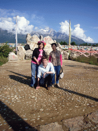 Tim, Miaomiao and Miaomiao`s mother at a rock with inscriptions in a Minority Village near Lijiang, with view on Jade Dragon Snow Mountain