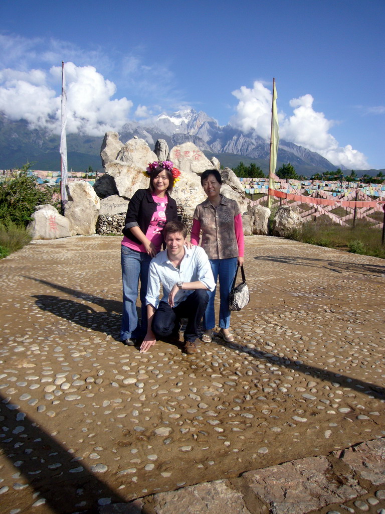 Tim, Miaomiao and Miaomiao`s mother at a rock with inscriptions in a Minority Village near Lijiang, with view on Jade Dragon Snow Mountain