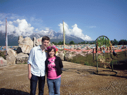 Tim and Miaomiao at a rock with inscriptions in a Minority Village near Lijiang, with view on Jade Dragon Snow Mountain