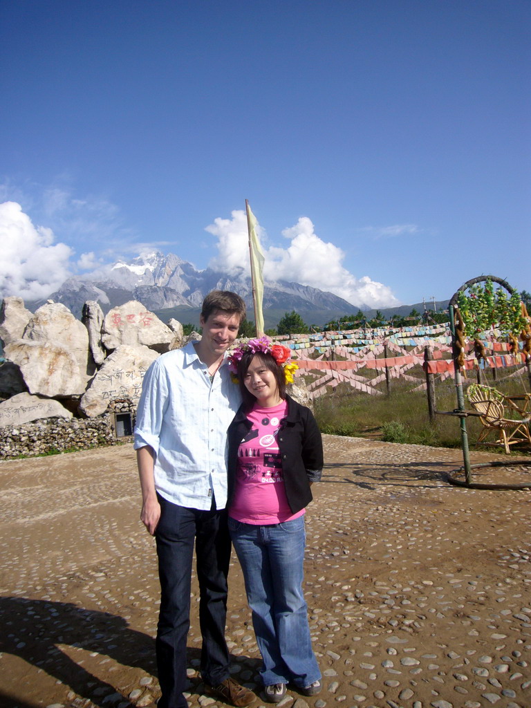 Tim and Miaomiao at a rock with inscriptions in a Minority Village near Lijiang, with view on Jade Dragon Snow Mountain