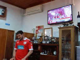 Waiter and TV with images of the championship of the S.L. Benfica soccer team at the A Gina Restaurant