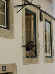 Woman with dog hanging from a window at the Rua de Bica de Duarte Belo street