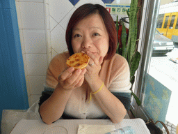 Miaomiao with a Pastéis de Nata cake at the Pastelaria Glacial restaurant at the Rua do Arsenal street