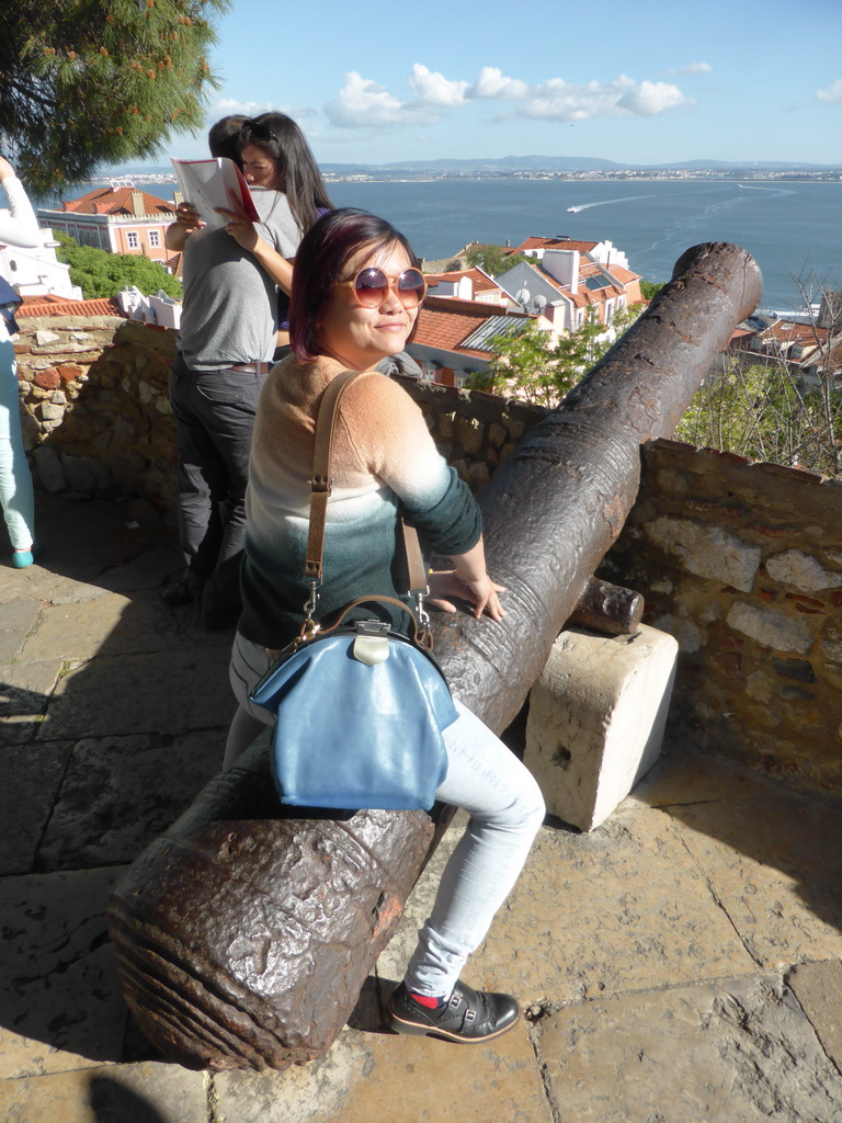 Miaomiao with a cannon at the Praça d`Armas square at the São Jorge Castle, with a view on the southeast side of the city and the Rio Tejo river