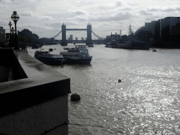 The HMS Belfast and other boats in the Thames river and the Tower Bridge, viewed from the shore on the northeast side of London Bridge