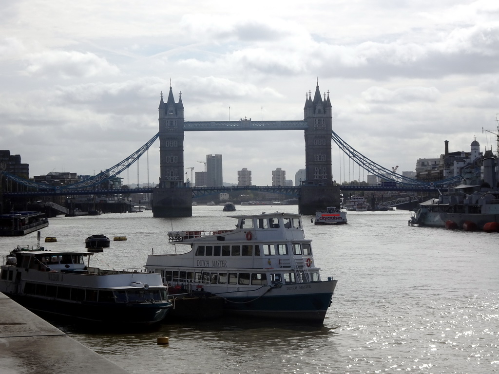 The HMS Belfast and other boats in the Thames river and the Tower Bridge, viewed from the shore on the northeast side of London Bridge