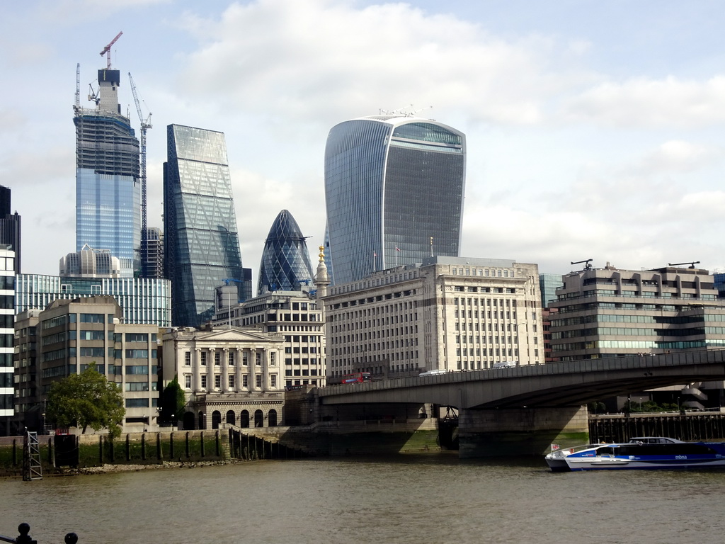 Boat in the Thames river, London Bridge, the Fishmongers` Hall, the 22 Bishopsgate building, under construction, the Leadenhall Building, the 30 St. Mary Axe building and the Sky Garden building, viewed from Cathedral Street