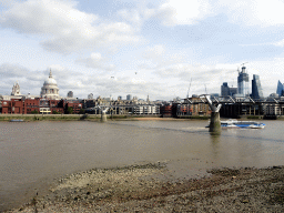 Boat in the Thames river, the Millennium Bridge, the towers and dome of St. Paul`s Cathedral, the 22 Bishopsgate building, under construction, the Leadenhall Building and the Scalpel building, viewed from the Bankside