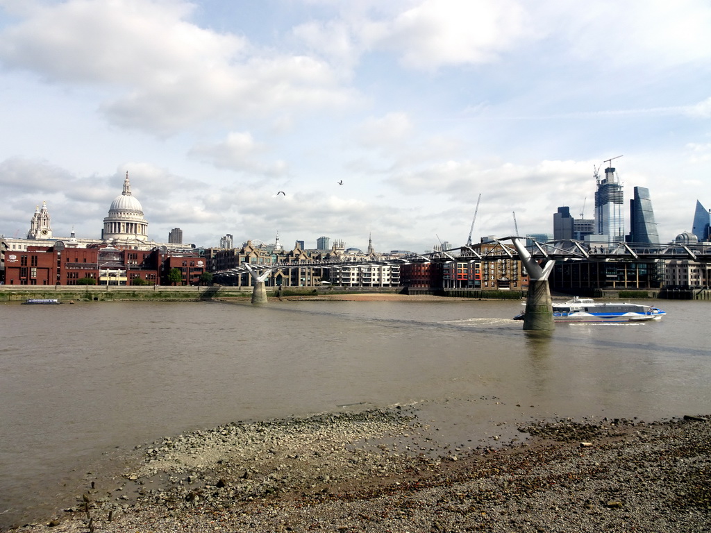 Boat in the Thames river, the Millennium Bridge, the towers and dome of St. Paul`s Cathedral, the 22 Bishopsgate building, under construction, the Leadenhall Building and the Scalpel building, viewed from the Bankside