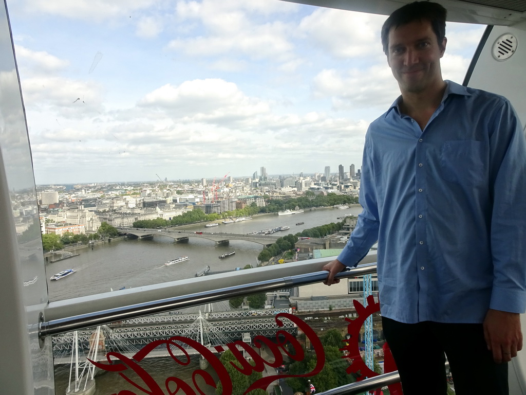 Tim in capsule 17 of the London Eye, with a view on boats in the Thames river, the Hungerford Bridge, the Golden Jubilee Bridges and the Waterloo Bridge