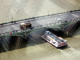 Tour boat going under the Westminster Bridge over the Thames river, viewed from capsule 17 of the London Eye