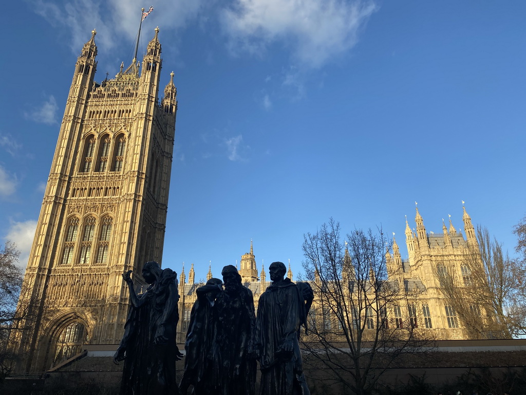 Sculpture `The Burghers of Calais` by Auguste Rodin at the Victoria Tower Gardens and the south side of the Palace of Westminster with the Victoria Tower